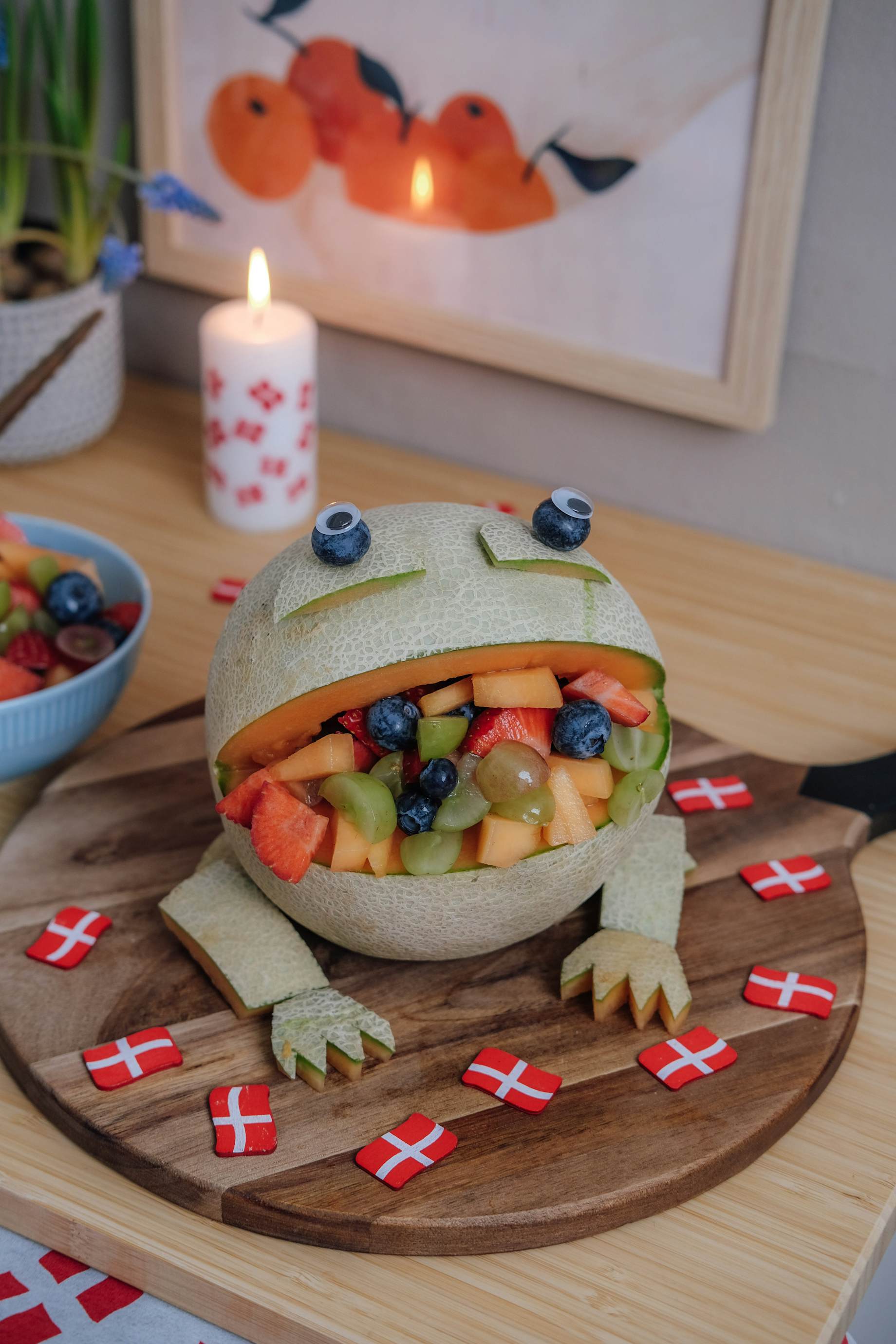 Melon skåret ud som en frø med åben mund. Munden er fyldt med frugt.