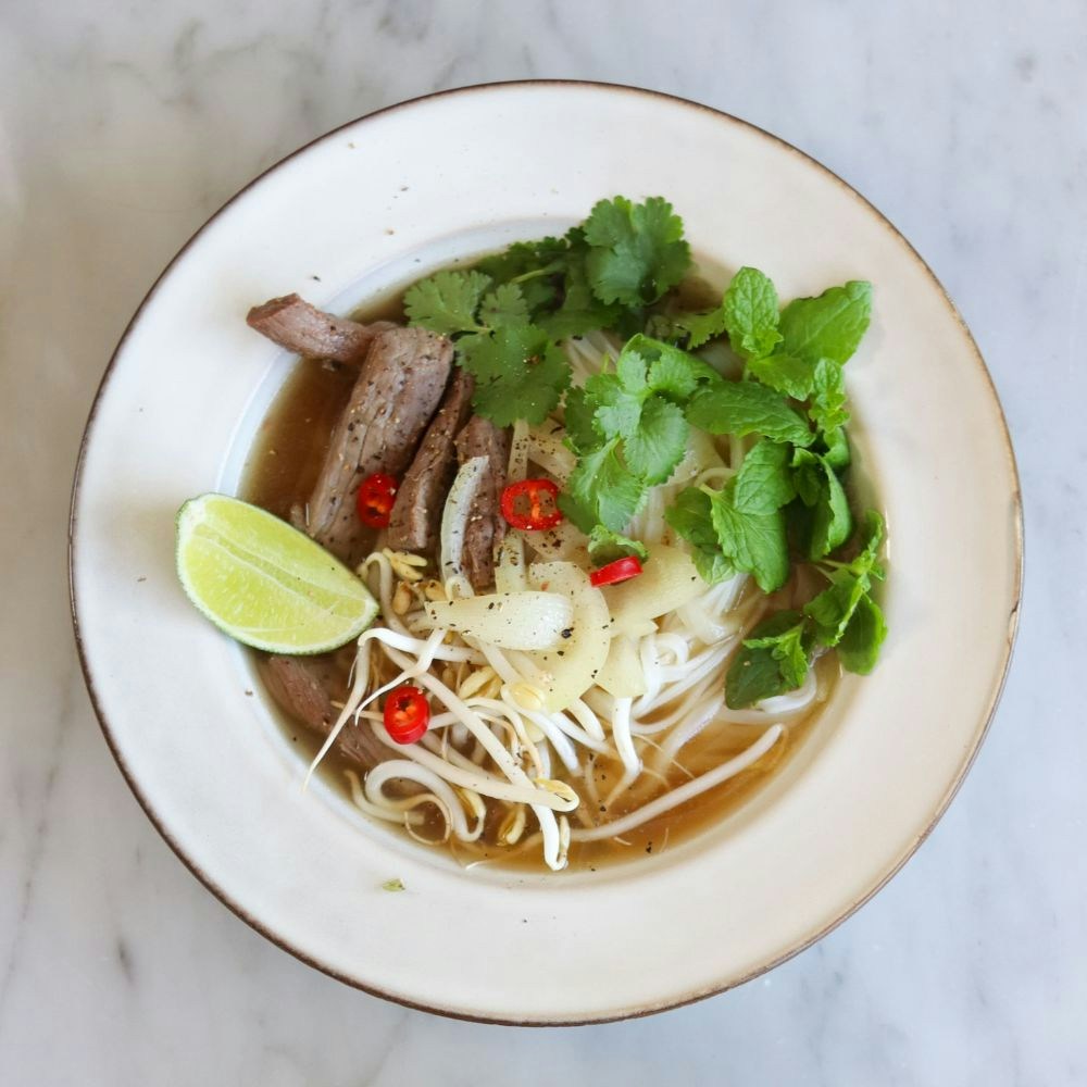 Pho suppe med oksekød, nudler, urter, chili og lime