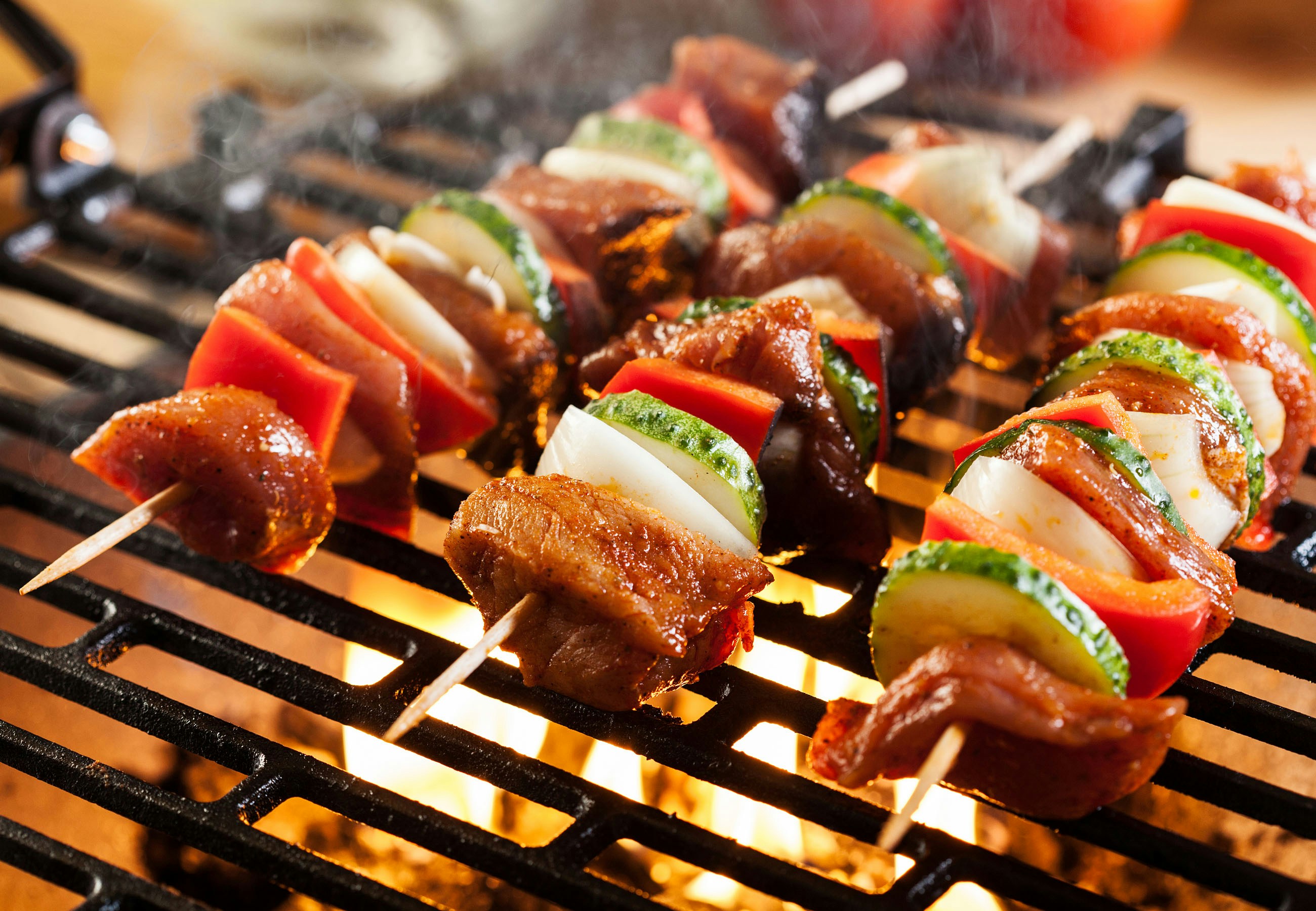 Grillspyd med grøntsager og kød på grill med direkte varme